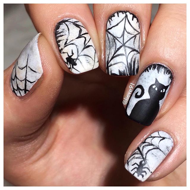white and black mani with a spider, spider web and a black cat